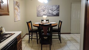 A dining area with a round table, four chairs, a ceiling fan, and artwork on the walls. - Urban Oasis in the Heart of OKC (Oklahoma City)
