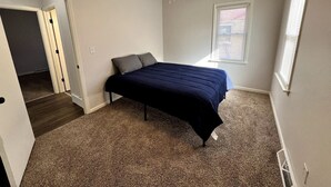Une chambre à coucher avec un lit, un ventilateur de plafond, une fenêtre et une porte.