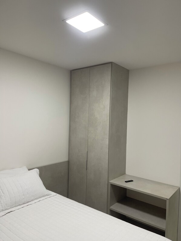 A bedroom with a bed, a wardrobe, and a desk with a chair.