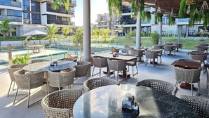 A rooftop bar with outdoor seating, a pool, and greenery.