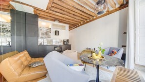 A modern living room with a high ceiling, a dining area with a marble table, and a kitchen in the background. - Paris Marais City Heart (Paris)