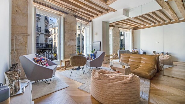 A spacious living room with a high ceiling, large windows, and a cozy seating area with a sofa and chairs. - Paris Marais City Heart (Paris)