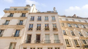 A multi-story building with a classical architectural style, featuring balconies with wrought iron railings and large windows. - Paris Marais City Heart (Paris)