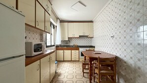 Una cocina compacta con microondas, estufa y mesa de comedor de madera.