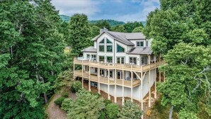A two-story house with a balcony, surrounded by dense forest.