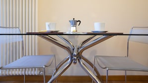 Ett modernt bord med en glasskiva och kromade ben, tillsammans med två metallstolar.