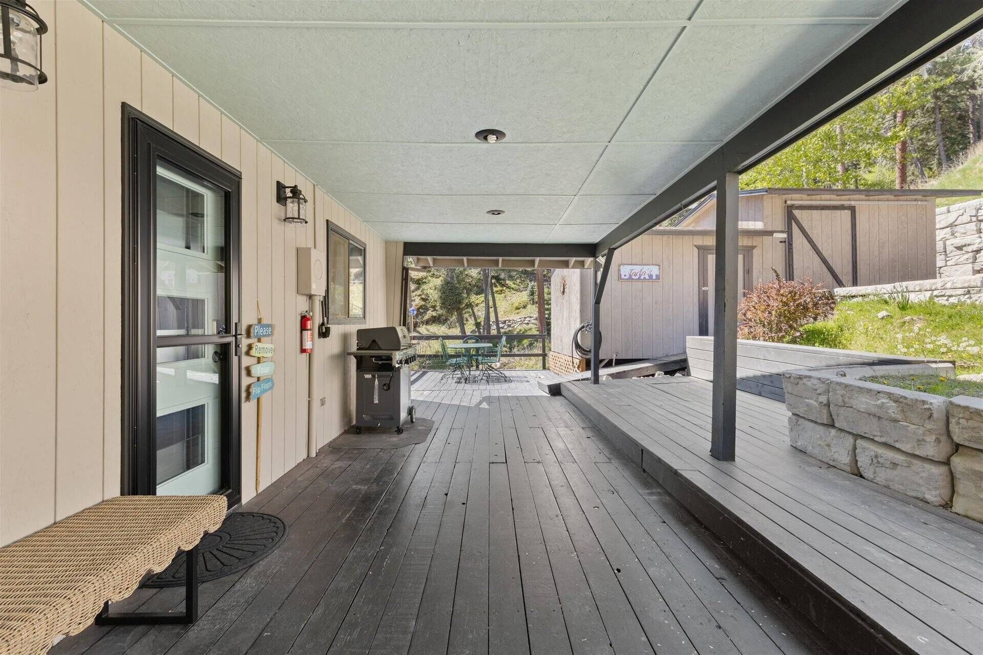 A covered outdoor area with a grill, seating, and a view of the surrounding landscape.