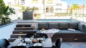 A rooftop terrace with a dining table set for four, a pool, and a seating area with cushions. - Modern Central Secure Cape Town 2bed Bantry Suite (Cape Town)