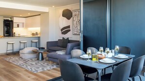 A modern living space with a dining area, a sofa, and a kitchen in the background. - Modern Central Secure Cape Town 2bed Bantry Suite (Cape Town)