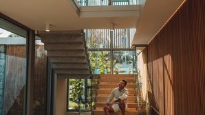 A modern interior with a glass balustrade, wooden flooring, and a pool.