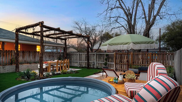Un patio trasero con un porche de madera, un jacuzzi y mobiliario exterior.