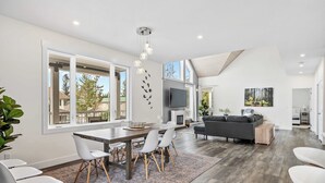 A spacious living area with a dining table, chairs, a sofa, and a TV. - Radiant Retreat | Sleeps 13 + Loft | Stunning View (Radium Hot Springs)