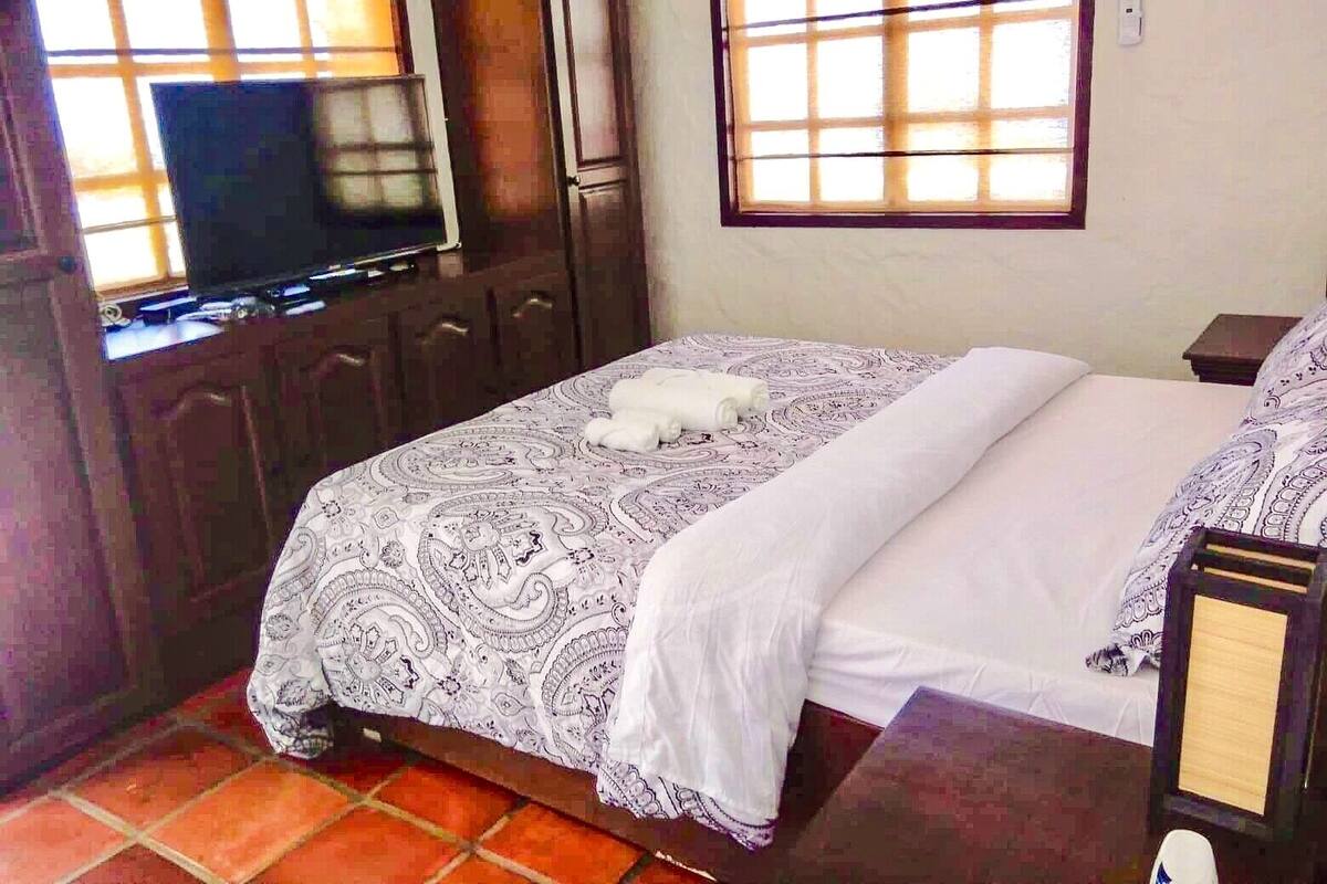 A bedroom with a bed, a television, and a window with a view.