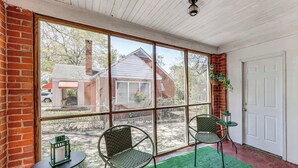 A room with large windows, two wicker chairs, a small table, and a green rug. - Walkable Masters Hub! 2 Miles to Augusta National (Augusta)