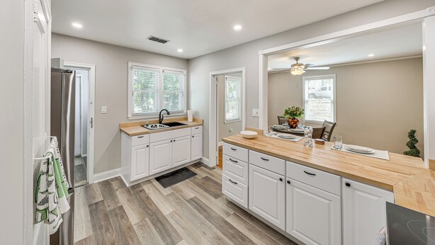 A modern kitchen with white cabinets, a wooden countertop, and a built-in sink. - Walkable Masters Hub! 2 Miles to Augusta National (Augusta)