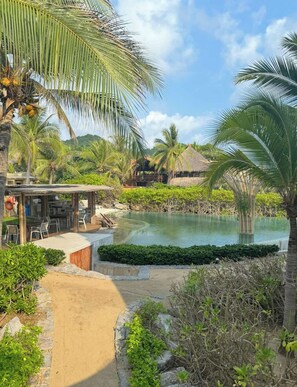 Un resort con piscina, area salotto esterna e vegetazione tropicale.