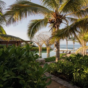 Un resort tropical con palmeras, piscina y vista a la playa.