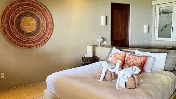 A bedroom with a bed, a ceiling fan, a wall-mounted lamp, and a circular woven rug. - Elegant Oceanview Suite Perfect Hideaway for two (La Majahua)