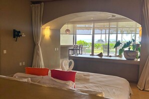Una camera d'albergo con un letto, una finestra vista esterna, un tavolo con sedie e una pianta in vaso.