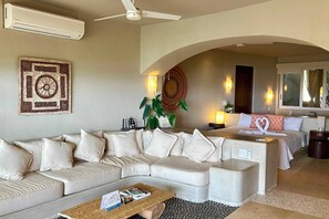 A hotel room with a sofa, a bed, a coffee table, and a wall-mounted air conditioner.