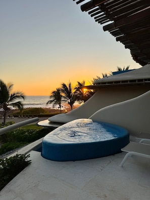 Zona de piscina con tobogán de agua, palmeras y vistas al atardecer.
