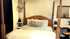Un letto a baldacchino con una testiera in legno, un comodino con una lampada e uno specchio appeso al muro.