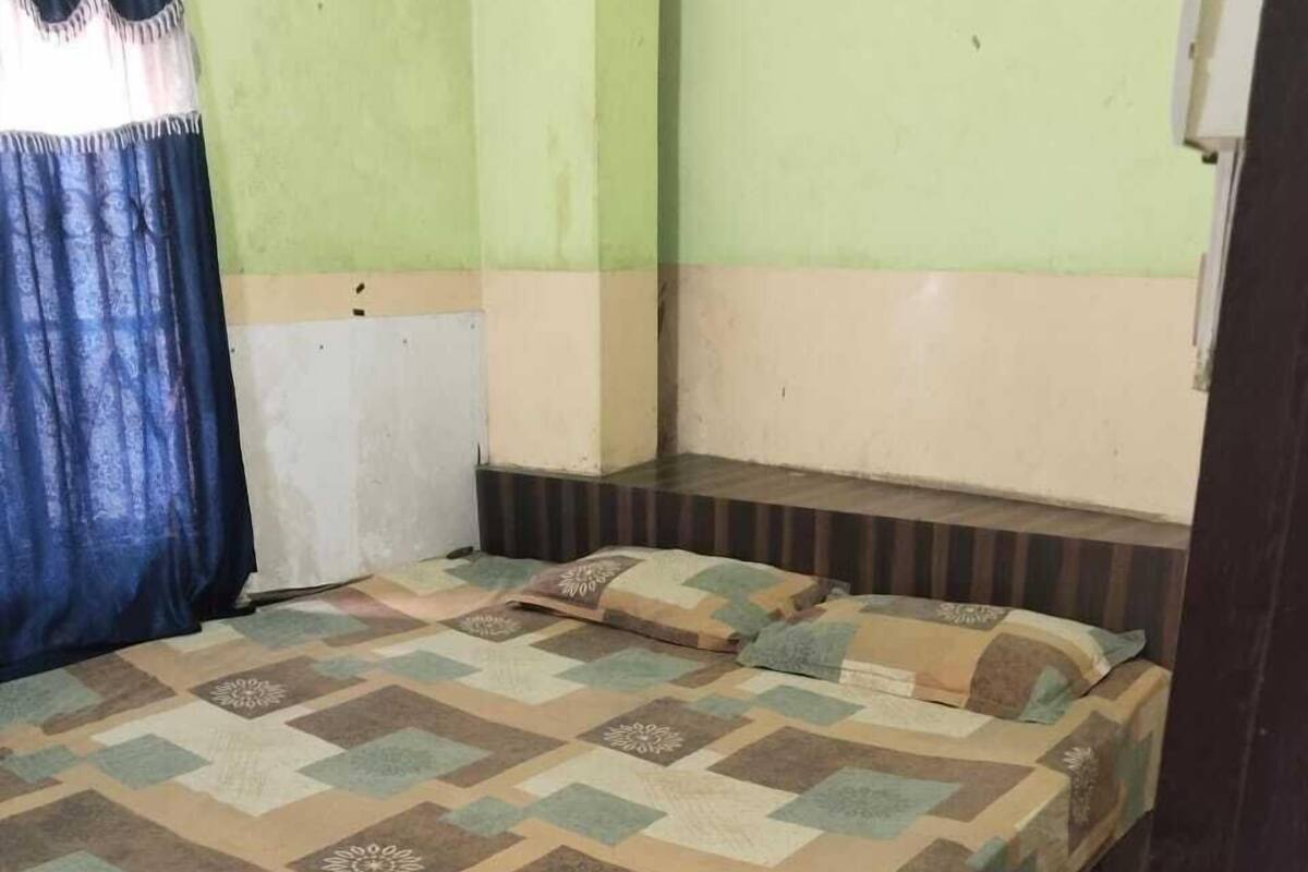 A room with a bed, a curtain, and a wall socket.