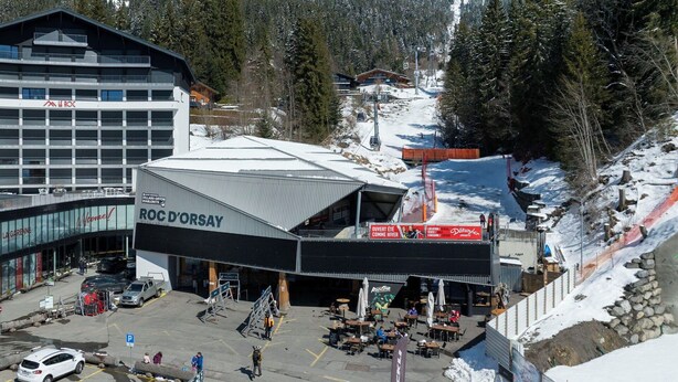 A ski resort with a prominent building labeled 'ROC D'ORSAY,' a parking area, and a mountainous backdrop. - Beautiful apartment for 2 guests with WIFI and balcony (Ollon)