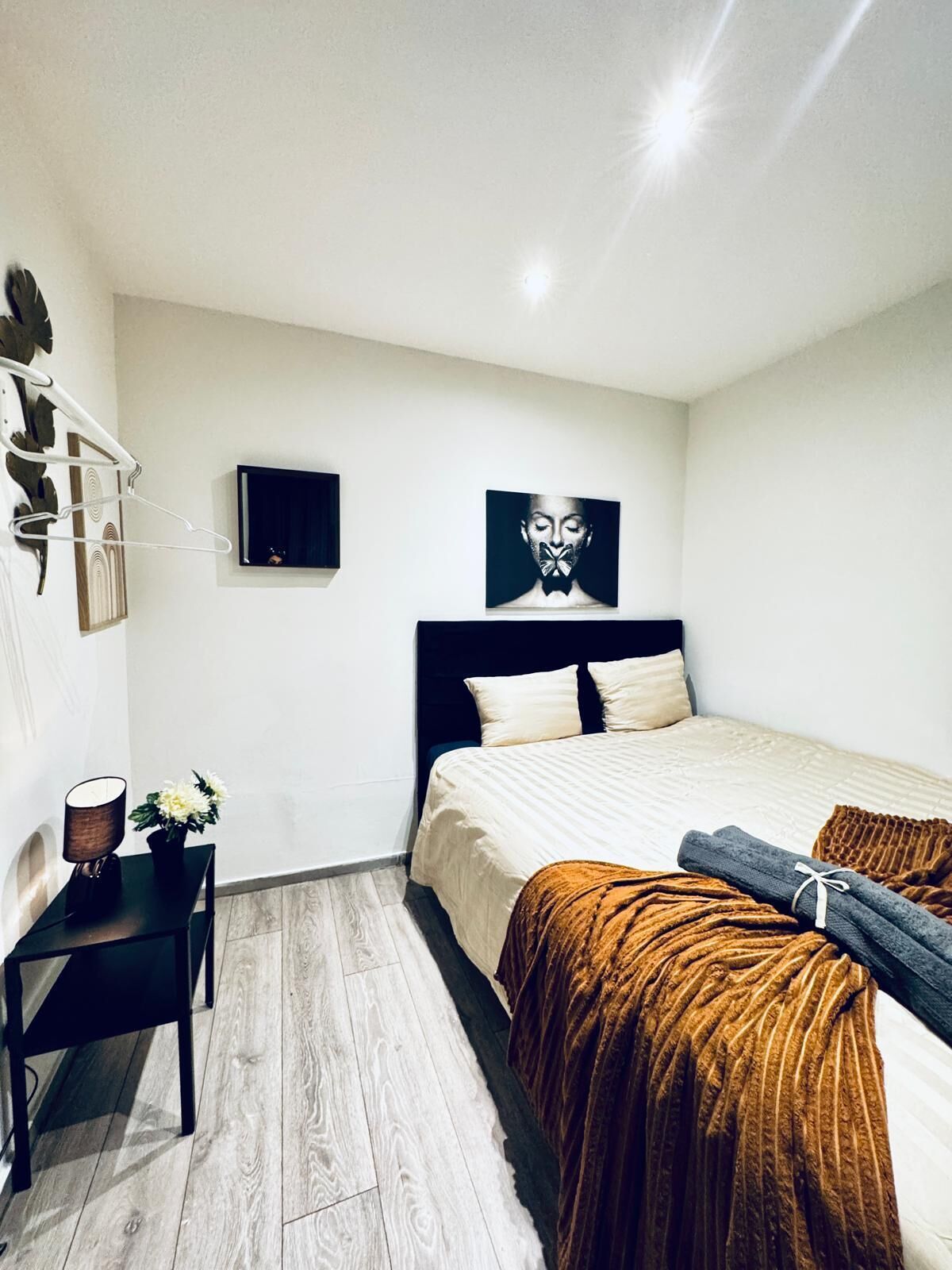 A modern bedroom with a bed, a bedside table, a lamp, and a wall-mounted TV.