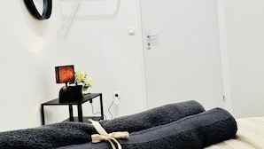 Une pièce avec un lit, une table de chevet avec une lampe et une porte.