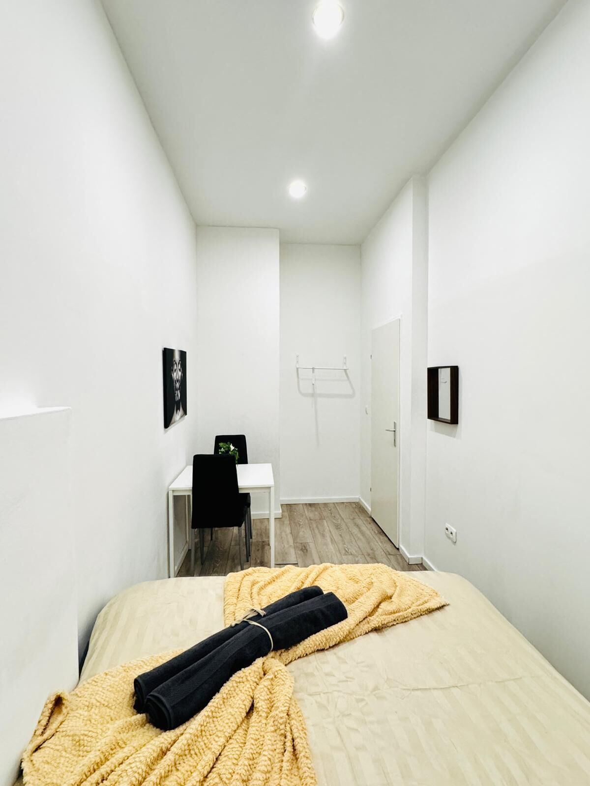 Ein Hotelzimmer mit Bett, Schreibtisch, Stuhl und Kleiderhaken.