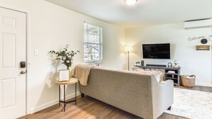 Un salon avec un canapé, une petite table d’appoint, une lampe et un téléviseur.
