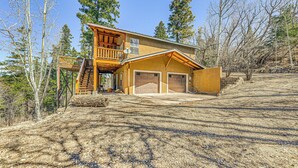 A two-story house with a wooden deck, a garage, and a stone staircase. - 2 Mi to Dtwn: Cloudcroft Home w/ Furnished Deck (Mayhill)