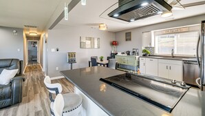 A modern kitchen with a central island, a dining area with a sofa and chairs, and a hallway leading to another room. - 5 Mi to Dtwn: Family-Friendly Home in Roanoke! (Roanoke)