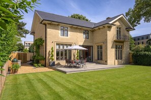 A two-story house with a patio, a barbecue grill, and a well-maintained lawn.