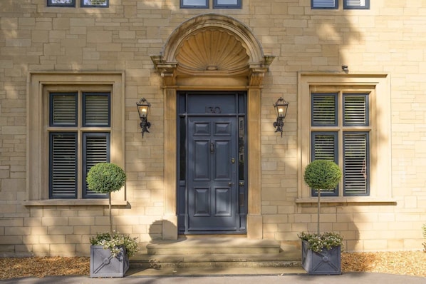 A building with a dark blue door, numbered 130, flanked by two windows with shutters.