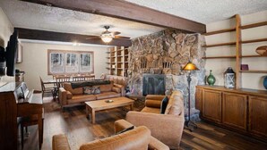 A cozy living room with a stone fireplace, wooden furniture, and a ceiling fan. - Colorado's Hidden Gem: Fish, Raft & Ride Horses in Scenic Mountain Setting (Almont)