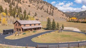 A two-story building with a flat roof, a driveway, and a fenced area with a horse-drawn carriage. - Colorado's Hidden Gem: Fish, Raft & Ride Horses in Scenic Mountain Setting (Almont)