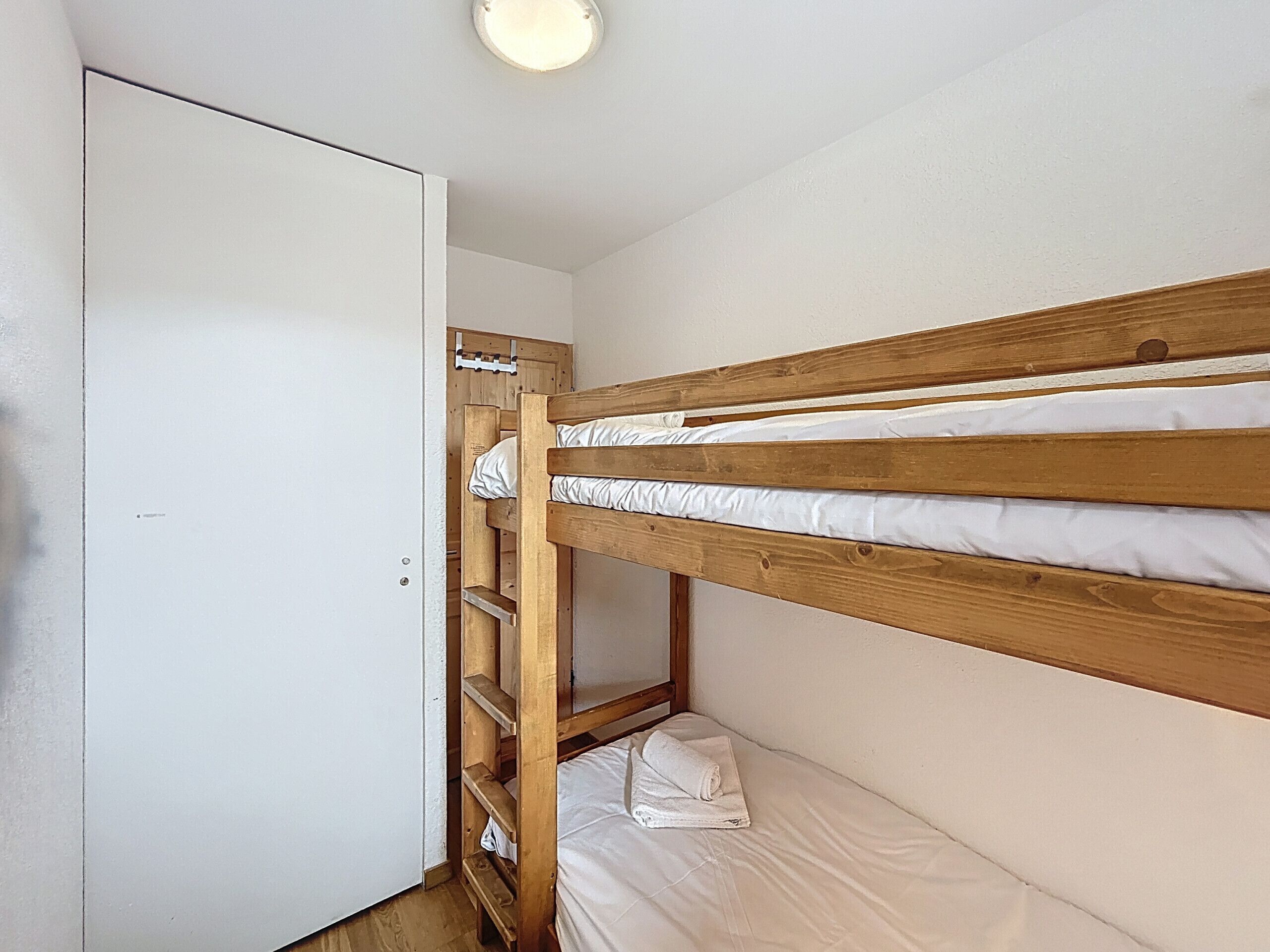 Une chambre avec un lit superposé, une armoire et une porte.