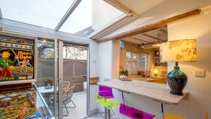 Una cocina moderna con un ventanal que da a un balcón, techo de madera y una lámpara de colores.