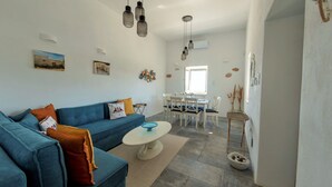 Ein modernes Wohnzimmer mit einem blauen Sofa, einem weißen Couchtisch und einem Essbereich mit Tisch und Stühlen.
