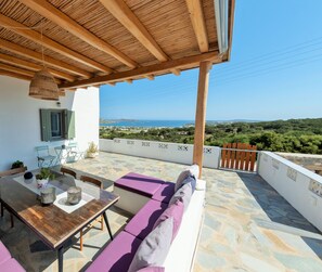 A covered outdoor seating area with a view of the sea.