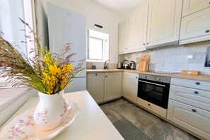 A modern kitchen with white cabinets, a built-in oven, and a window.