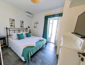 A bedroom with a bed, a bedside table, a television, and a window with curtains.