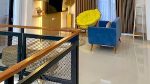 A modern living room with a blue sofa, a yellow chair, and a TV on a wooden cabinet. - DIRUMA SADJA HOME VILLA (Ngemplak)