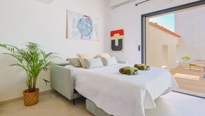Een moderne slaapkamer met een bed, een potplant en uitzicht door een glazen deur.