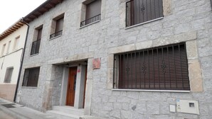 A stone building with a wooden door, barred windows, and a small sign. - Holiday Home in Castilla-León with Pool (Bernuy Salinero, Ávila)