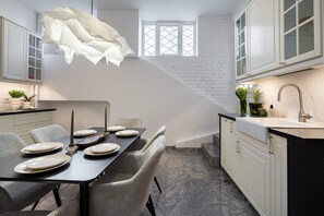 Et moderne køkken med hvide skabe, en sort bordplade og et marmorgulv.