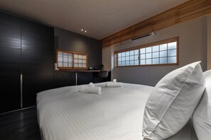 Ein modernes Hotelzimmer mit einem großen Bett, einer Holzbodenverkleidung, einem großen Fenster und einer dunklen Wand.