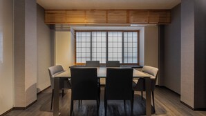 Un salón de conferencias con una gran mesa, cuatro sillas y un ventanal con diseño de cuadrícula.